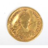 A Roman gold Solidus coin with helmeted bust facing holding a spear and shield,