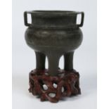 A Chinese Ming dynasty bronze tripod censor on later carved hardwood stand.