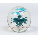 A glass paperweight decorated with dolphins and aquatic weeds.