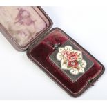 A cased white metal rectangular locket enamelled with a lozenge of stylized flowers, 4cm.