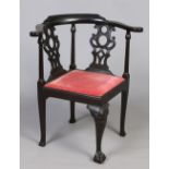 A Victorian ebonized corner chair with pierced splats and raised on a carved cabriole support.