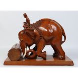 An Indian carved hardwood and ivory statue of a boy riding an elephant moving a large log and