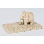 A 19th century Indian carved ivory model of an elephant raised on a moulded mammoth tooth plinth,