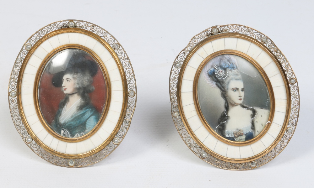 A pair of 20th century portrait miniatures in oval brass filigree strut frames, 13.5cm.