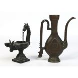 A Romanesque 19th century bronze oil lamp with a horses head handle and ornamented with a goats