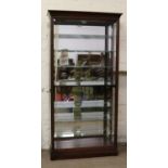 A Howard Miller carved mahogany tall standing display cabinet with mirrored interior and light