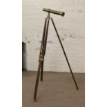 A brass telescope mounted on a hardwood tripod.