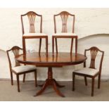 An oval centre pedestal yew wood extending table with built in bi fold leaf and four spade foot leg