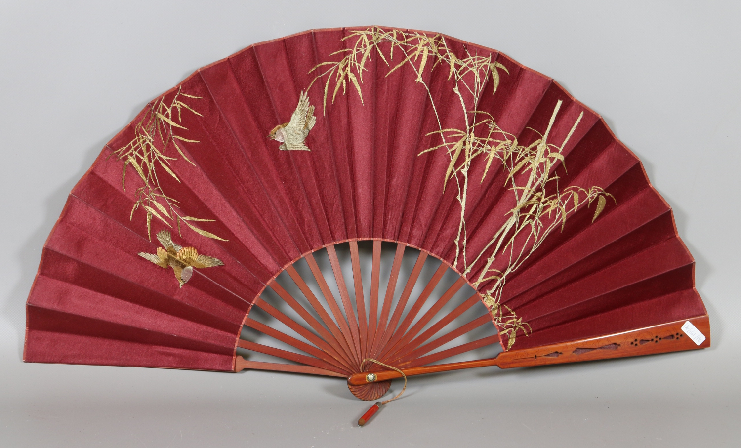 An early 20th century Oriental bamboo fan, with silk needlework depicting birds and bamboo.