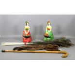 A pair of painted plaster cast figurines, a walking stick,