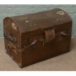 A canvas leather bound dome top travel trunk with heavy leather straps and lock protector and