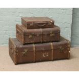 A wooden bound travel trunk, a smaller trunk and a small leather suitcase.