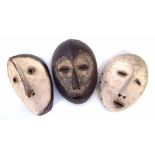 Three Lega masks carved with handles to the reverse, 25cm high All lots in this Tribal and African