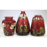 Three Minton Secessionist ware vases, tube lined with stylised foliate patterns on red grounds,