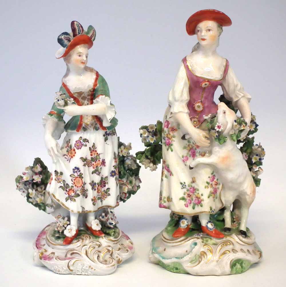 Two Derby figures of ladies circa 1770, modelled standing in front of floral bocages on scrolled