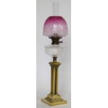 Brass Corinthian cluster column table oil lamp with a cut glass reservoir and pink glass shade,