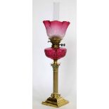 Brass Corinthian column table oil lamp with a ruby glass reservoir and frosted trumpet shade, height