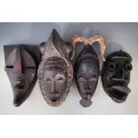 Four masks, carved in Bete, Guro, Yaure, and Lulua tribal styles, the largest measures 42cm high All