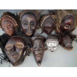 Eight masks carved in Chokwe and similar tribal styles, one made from a bone section (bottom