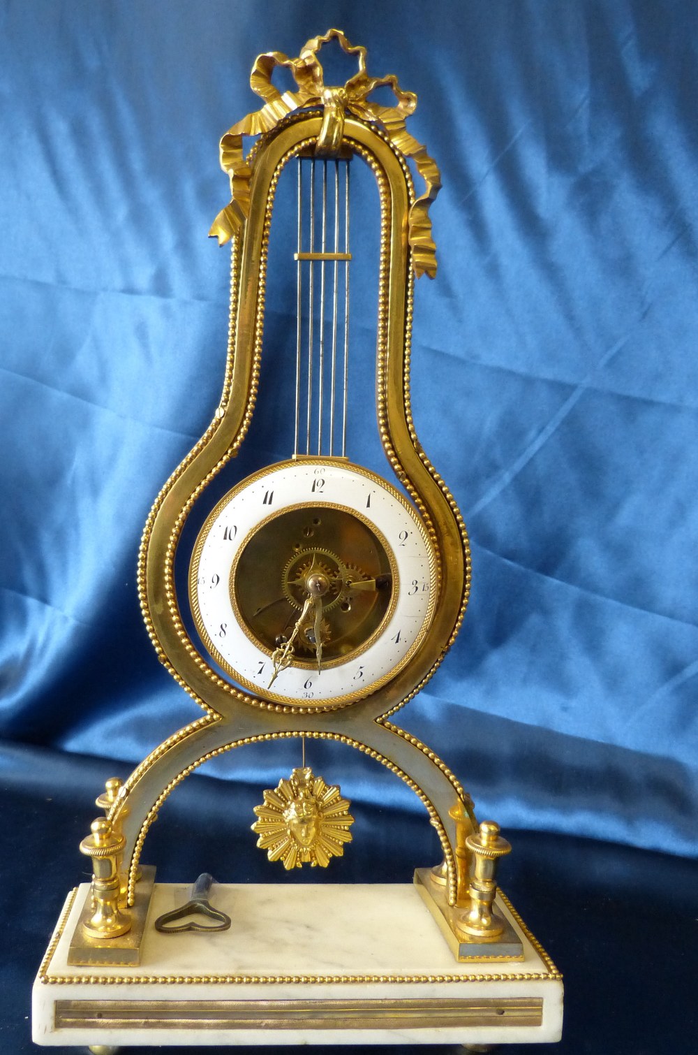 A 19th Century French Directoire Ormolu Lyer Shape Timepiece having white enamel dial,