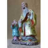 An Oriental China Group of an elderly gentleman and child holding scrolls,