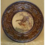 A Terracotta Circular Plaque depicting bird being attacked with all over raised leaf and scroll