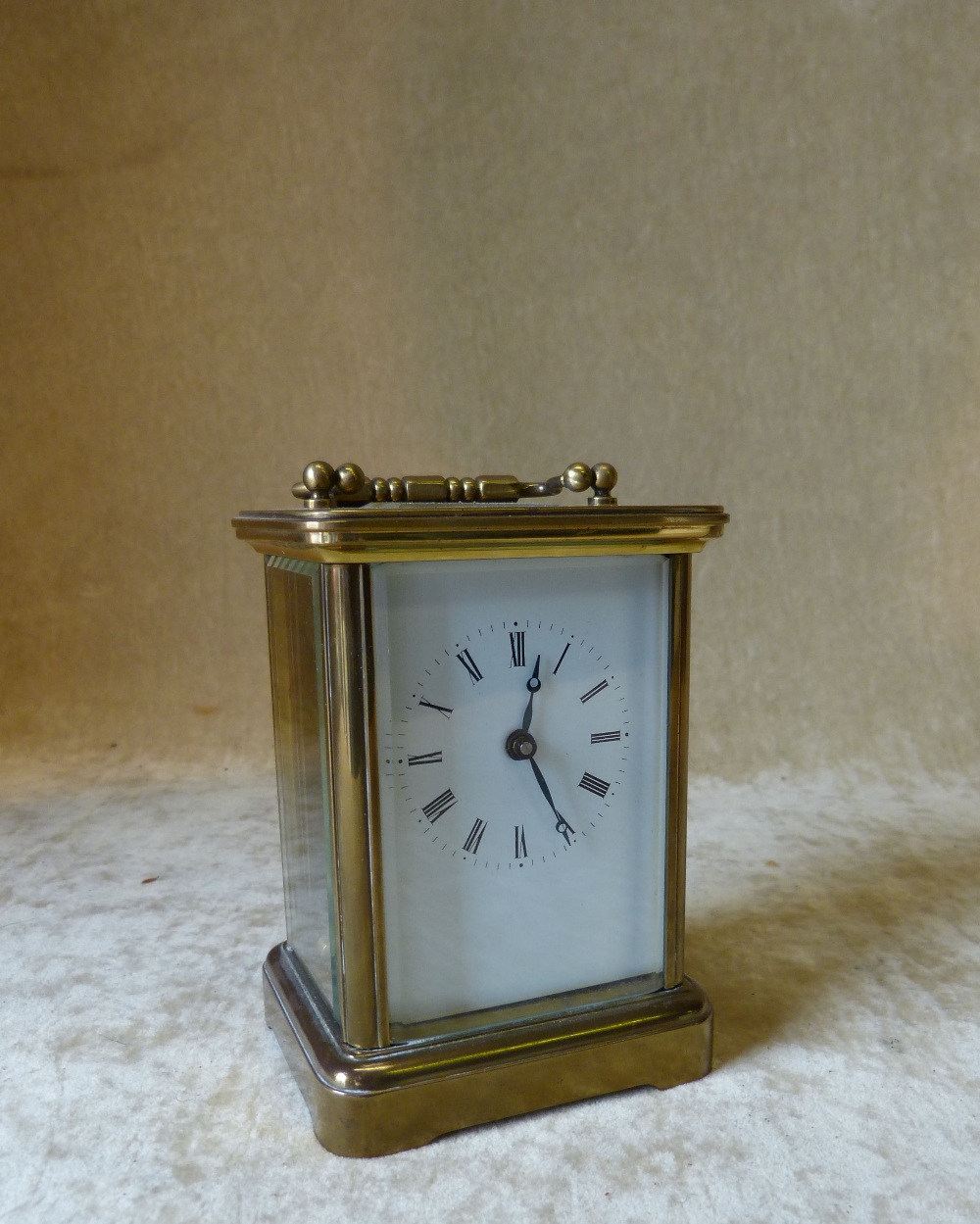 A Brass Carriage Clock having white enamel dial, Roman numerals with swing overhead handle,