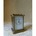 A Brass Carriage Clock having white enamel dial, Roman numerals with swing overhead handle,