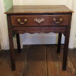 A small oak side table, fitted with a drawer to the shaped frieze, raised on square chamfered legs,