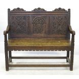 An oak bench seat settle, with three carved panels to the back,