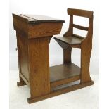 An early 20th century pitch pine and oak school desk, with fixed chair and cupboard below,