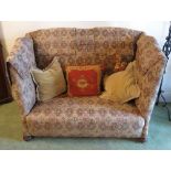 A high back two seat sofa, raised on short turned bun feet,