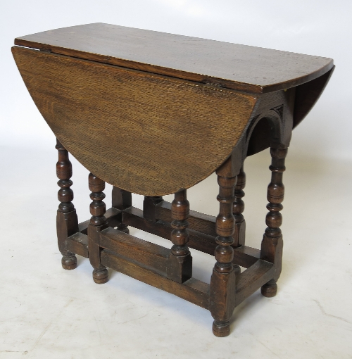 An oval oak gate leg table, raised on bobbin turned legs,