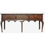 A 19th century oak dresser base, fitted with three drawers to the shaped frieze,