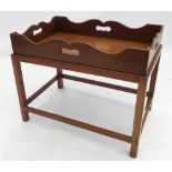 A mahogany rectangular tray, with shaped gallery edge and cut out handles, on separate base,