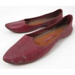 A pair of red leather slip on shoes, with label to the leather sole,