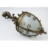 A brass hanging light fitting, the column decorated with plain scrolls and scrolling leaves,