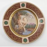 A Viennese plate, decorated with a young girl bathing with child, to a maroon, gilt,