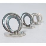 A cased set of four silver menu holders, formed as horse shoes with circles behind,
