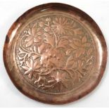 A Keswick School of Industrial Arts copper circular dish, embossed with flowers and leaves,