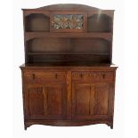 An Art Nouveau oak sideboard, the upper section with shelves and being part glazed,