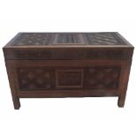 A camphor chest, with geometric carving to the front, lid and sides, raised on stile feet,
