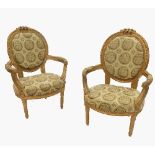 A pair of giltwood salon chairs, with oval upholstered backs, and outswept arms,