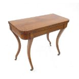 A 19th century rosewood foldover games table, with boxwood line inlay, raised on four sabre legs,