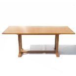 An oak dining table, raised on four chamfered square legs, with sledge feet united by a stretcher,