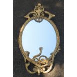 A gilt framed oval wall mirror, the frame decorated with flower heads,