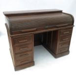 An early 20th century oak roll top desk, raised on two pedestals with four graduated drawers,