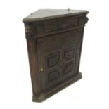 A heavily carved oak corner cupboard, opening to reveal a shelf with lion mask,