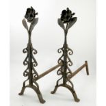A pair of metal fire dogs, with a stylised flower head and foliage,