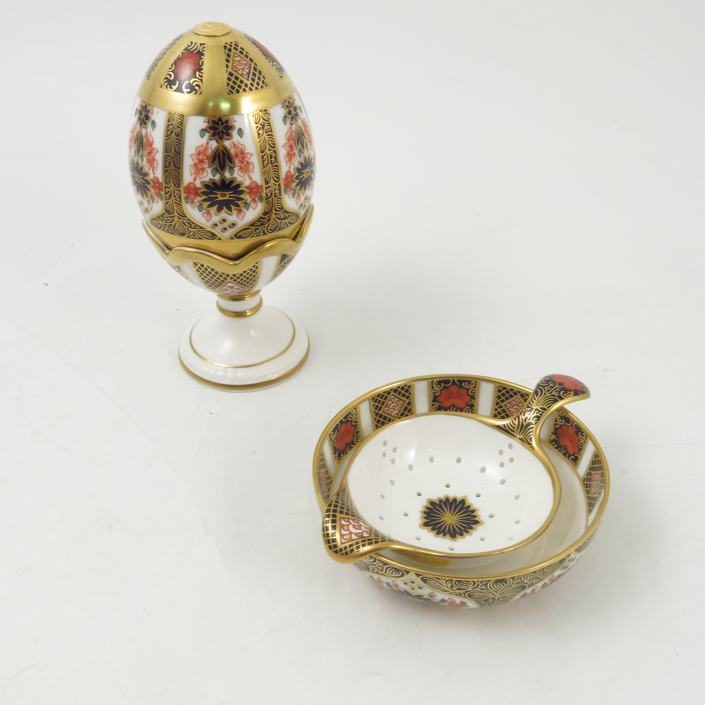 A Royal Crown Derby tea strainer and stand, together with an ornamental egg and cup,